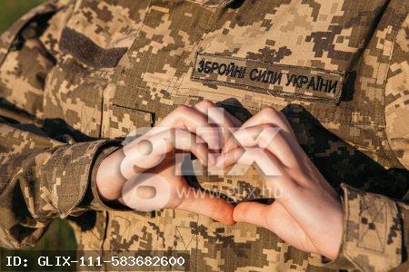 Close up female soldier showing heart love shape sign on velcro patch military uniform. Armed Forces of Ukraine. Woman serving in ukrainian army.