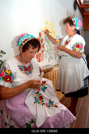 Kalocsai népviseletbe öltözött asszonyok falat pingálnak-stock-foto