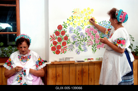 Kalocsai népviseletbe öltözött asszonyok falat pingálnak-stock-foto