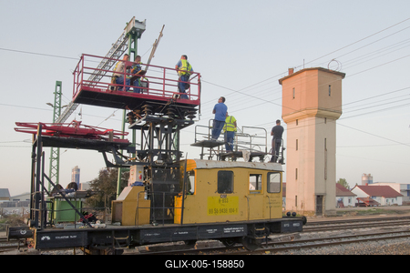 A hajdúszoboszlói vasútállomás átépítése során, az új felsővezetékekett teszik fel az erősáramű felsővezeték szerelők. A háttérben a lebontásra ítélt gőzmozdony töltő víztorony látható.-stock-foto