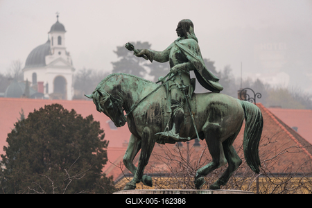 statue of Janos Hunyadi on Szechenyi Square in Pecs, Hungary with chapel at background-stock-foto