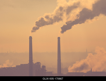 Smoking factory chimneys in morning backlit by rising sun-stock-foto