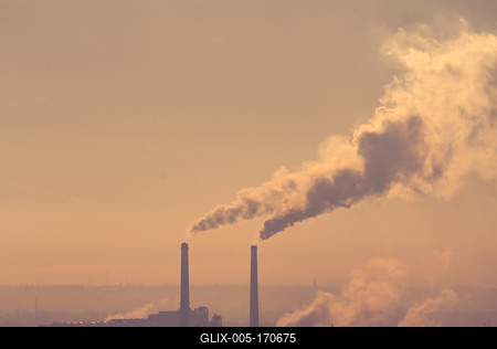 Smoking factory chimneys in morning backlit by rising sun-stock-foto
