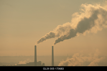 Smoking factory chimneys in morning backlit by rising sun-stock-foto