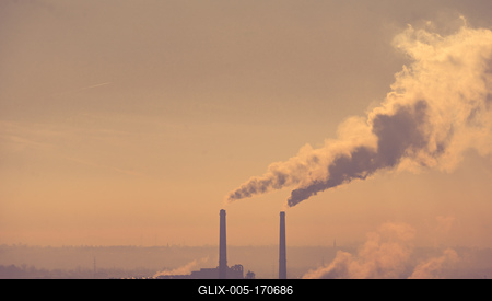 Smoking factory chimneys in morning backlit by rising sun-stock-foto