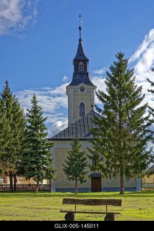 Panyola református templom hátulról egy park paddal meg fenyőfákkal-stock-foto