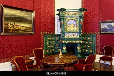 Gödöllő királyi kastély kandaló szoba zöld csempékkel, piros szövet tapéta, képek, ovális asztal székekkel-stock-foto