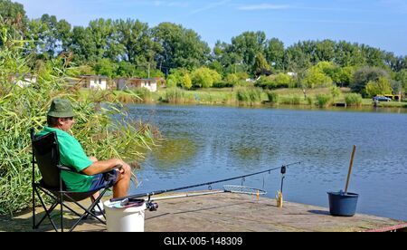 Horgász kényelmesen űl a székben és várja a kapást a martfűi horgásztónál-stock-foto