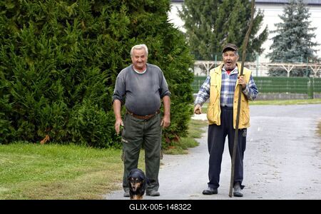 Két igazi szatmári férfi egy tacskóval az utcán, Panyolában-stock-foto