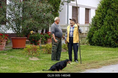 Két igazi szatmári ember meg tacskó, férfiak beszélgetnek egy leander előtt-stock-foto