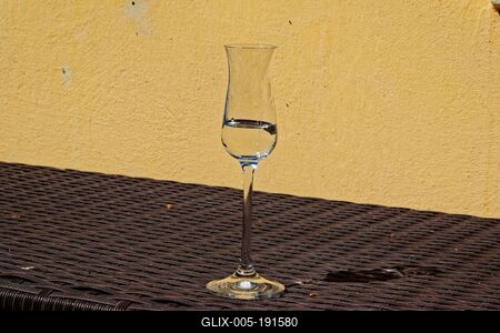 Egy pohár pálinka egy fonott asztalon sárga házfal elõtt-stock-foto