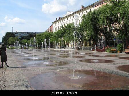 Szolnok, 2016. szeptember 3.A Kossuth tér, Szolnok fõtere szökõkútjaival. Balra a Sétáló ifjú pár szobor részlete. Kligl Sándor alkotása 2008-ból.-stock-foto