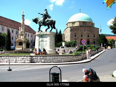 Pécs, 2009. június 15.Pécs központi tere, a Széchenyi tér. Elõtérben Hunyadi János lovasszobra (Pátzay Pál alkotása, 1956), Balra a Szentháromság szobor (Kiss György mûve, 1908), hátul Gázi Kaszim pasa dzsámija (XVI. szd. közepe).-stock-foto