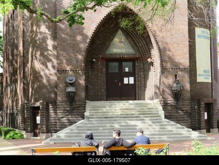 People sitting on a bench in font of the reformed church - Szeged-stock-foto