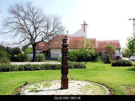 Gyál, 2010. április 24.A gyáli 1848-as és 1956-os szabadságharcnak emléket állító kopjafa. Mögötte az első gyáli templom, melyet Szilvási Sándor plébános alakított templommá bálteremből 1948-ban.-stock-foto