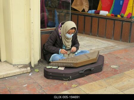 An Iranian woman strumming a zither in front of the Grand Bazaar in Tehran-stock-foto