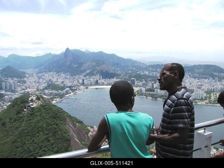 Rio de Janeiro, 25 January 2012Father and son enjoy the beauty of Rio in the Urca mountain. Below the Botafogo Bay, to the left is Corcovado with the Statue of Christ, to the left a section of the wire ropeway.Apa ?s fia Rio sz?ps?geiben gy?ny?rk?dik az Urca hegyen. Alattuk a Botafogo ?b?l, balra a Corcovado a Krisztus szoborral, balra lent a dr?tk?t?lp?lya egyik szakasza.-stock-foto