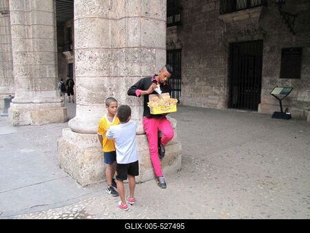 Havana, 25 January 2015Candy vending cuban young boy in Plaza de Armas.?dess?get ?rus?t? kubai fiatalember, mellette gyerekekkel, az ?v?ros f?ter?n, a Plaza de Armas-on.-stock-foto