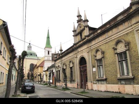 V?c, 2016. m?rcius 27.A Gasparik K?zm?r utca. Jobbra a 8. sz. alatti, 1900-as ?vek elej?n ?p?lt v?dett lak??p?let. Jobbra fentebb a Karolina k?polna tornya. Szemben a v?ci sz?kesegyh?z kupol?ja. Balra parkol? aut?.-stock-foto