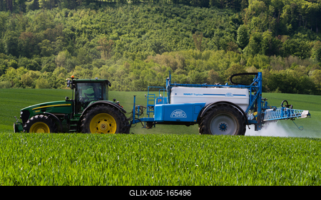 A farmer spraying on the spring wheat field with a John Deere tractor and a mamut topline sprayer.-stock-foto