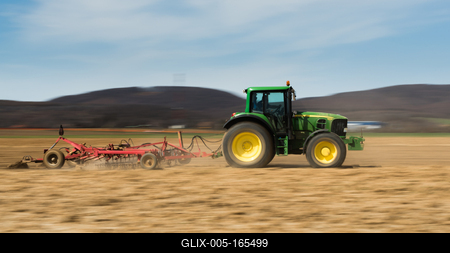 A farmer plowing with a John Deere tractor. Sunny day on the field.-stock-foto