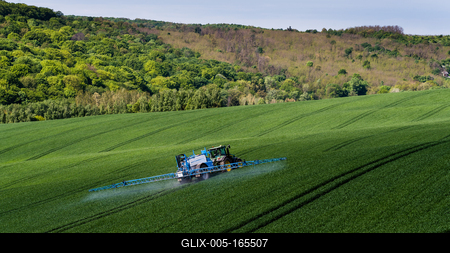 A farmer spraying on the spring wheat field with a John Deere tractor and a mamut topline sprayer.-stock-foto