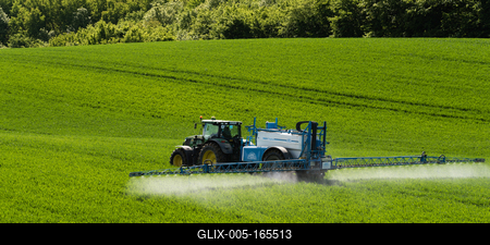 A farmer spraying on the spring wheat field with a John Deere tractor and a mamut topline sprayer.-stock-foto