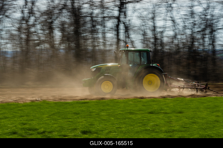 A farmer is plowing with a John Deere tractor. Sunny day on the field. It's a panning shot, that cause the blurry background and foreground.-stock-foto