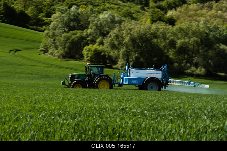 A farmer spraying on the spring wheat field with a John Deere tractor and a mamut topline sprayer. Panning shot.-stock-foto