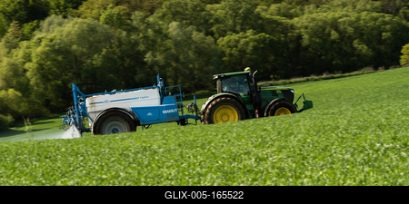 A farmer spraying on the spring wheat field with a John Deere tractor and a mamut topline sprayer. Panning shot.-stock-foto