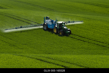A farmer spraying on the spring wheat field with a John Deere tractor and a mamut topline sprayer.-stock-foto