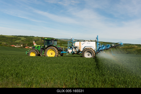 A farmer spraying on the spring wheat field with a John Deere tractor and a mamut topline sprayer. Panning shot.-stock-foto