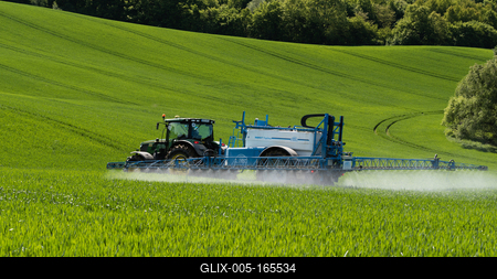 A farmer spraying on the spring wheat field with a John Deere tractor and a mamut topline sprayer.-stock-foto
