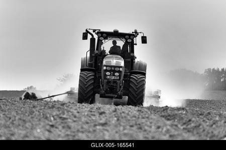 A farmer working on the field with a John Deere tractor. Black and white.-stock-foto