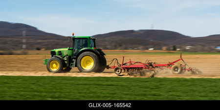 A farmer is plowing with a John Deere tractor. Sunny day on the field. It's a panning shot, that cause the blurry background and foreground.-stock-foto