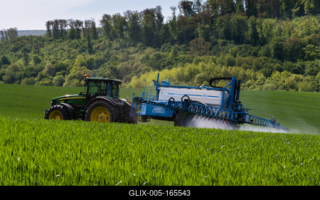 A farmer spraying on the spring wheat field with a John Deere tractor and a mamut topline sprayer.-stock-foto