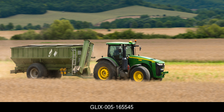 The farmer is going with a John Deere 8335R tractor and a Fliegl ULW trailer to load the harvested seeds.-stock-foto