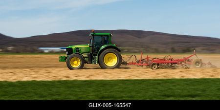 A farmer is plowing with a John Deere tractor. Sunny day on the field. It's a panning shot, that cause the blurry background and foreground.-stock-foto