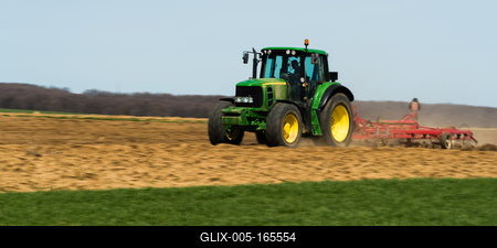 A farmer is plowing with a John Deere tractor. Sunny day on the field. It's a panning shot, that cause the blurry background and foreground.-stock-foto