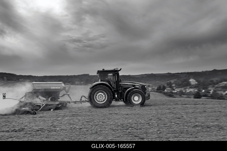 A farmer sowing with a John Deere tractor and a Horsch Pronto 4dc seeding machine. It's a panning shot, that cause the blurry background. Black and white.-stock-foto