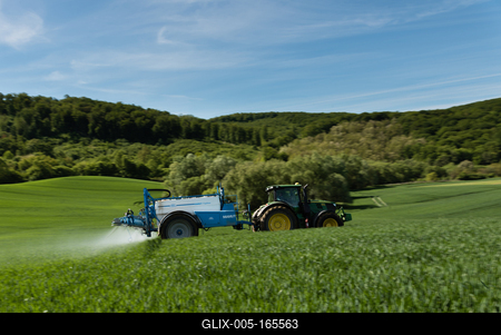 A farmer spraying on the spring wheat field with a John Deere tractor and a mamut topline sprayer. Panning shot.-stock-foto