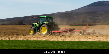 A farmer is plowing with a John Deere tractor. Sunny day on the field. It's a panning shot, that cause the blurry background and foreground.-stock-foto