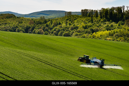 A farmer spraying on the spring wheat field with a John Deere tractor and a mamut topline sprayer.-stock-foto