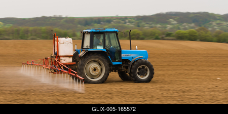 A farmer spraying with a Landini Evolution 9880 tractor. It's a panning shot, that's cause the blurry in the back and foreground.-stock-foto