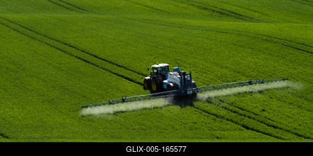 A farmer spraying on the spring wheat field with a John Deere tractor and a mamut topline sprayer.-stock-foto