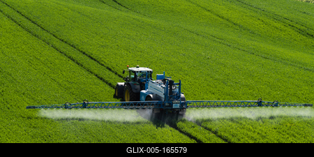 A farmer spraying on the spring wheat field with a John Deere tractor and a mamut topline sprayer.-stock-foto