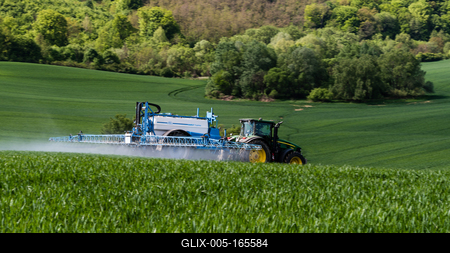 A farmer spraying on the spring wheat field with a John Deere tractor and a mamut topline sprayer.-stock-foto