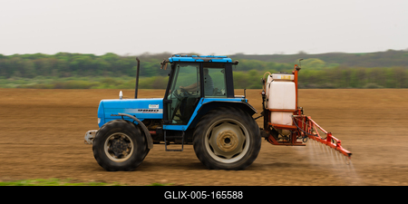 A farmer spraying with a Landini Evolution 9880 tractor. It's a panning shot, that's cause the blurry in the back and foreground.-stock-foto