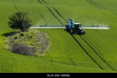 A farmer spraying on the spring wheat field with a John Deere tractor and a mamut topline sprayer.-stock-foto