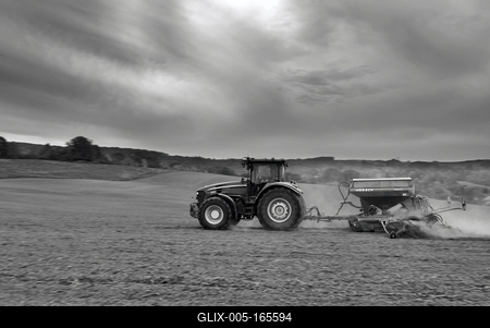A farmer sowing with a John Deere tractor and a Horsch Pronto 4dc seeding machine. It's a panning shot, that cause the blurry background. Black and white.-stock-foto